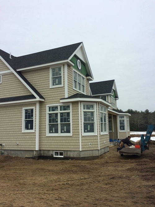 A newly constructed home with beige shake siding.