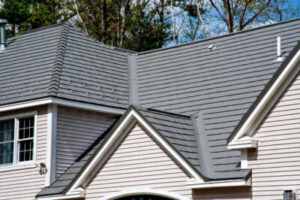 Close up of a light gray house with a darker gray shingle roof
